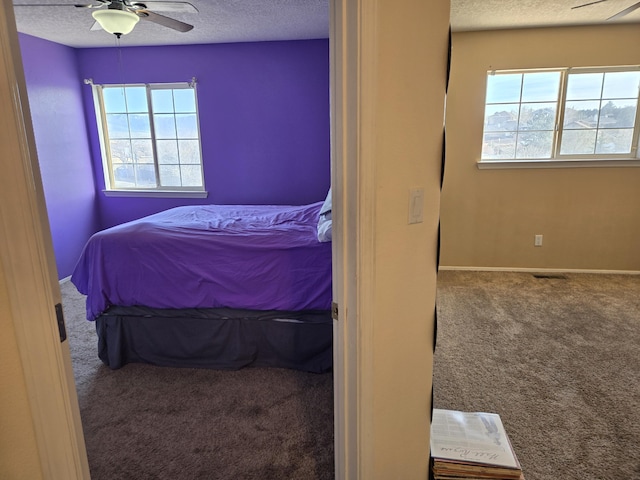 bedroom featuring ceiling fan, multiple windows, a textured ceiling, and carpet flooring