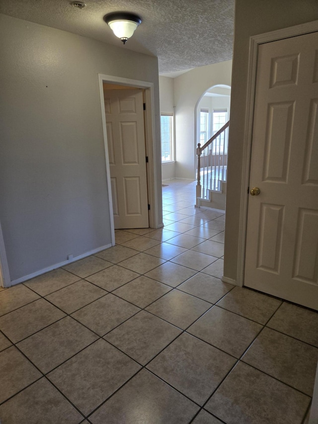 empty room featuring a textured ceiling and light tile patterned floors