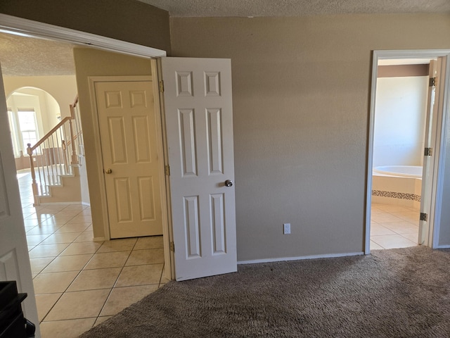 tiled empty room with a textured ceiling