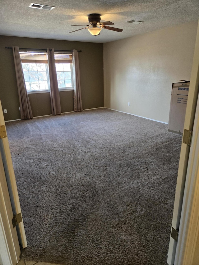 carpeted spare room featuring ceiling fan and a textured ceiling