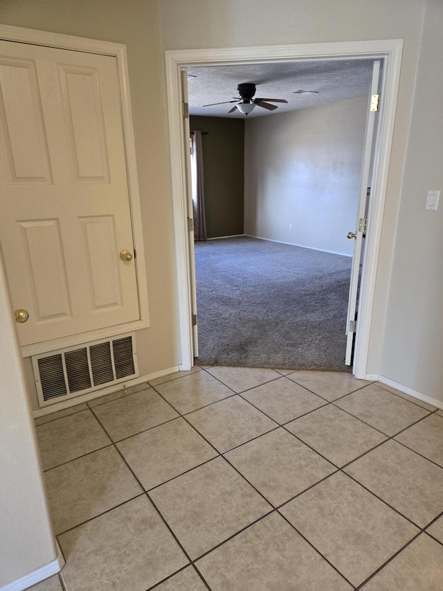 corridor featuring a textured ceiling and light tile patterned floors