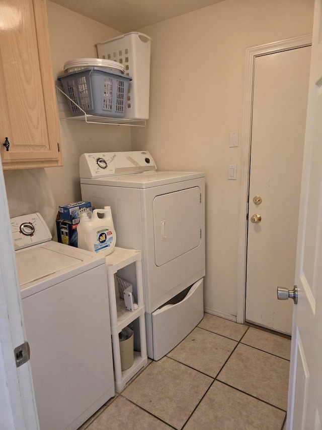 laundry area with light tile patterned flooring, cabinets, and washer and clothes dryer