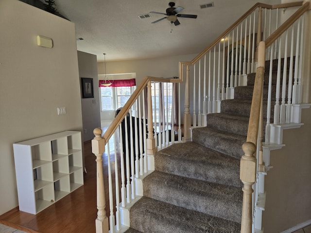 stairway featuring ceiling fan and wood-type flooring