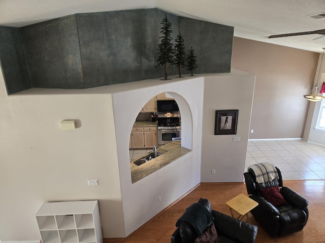 living room featuring ceiling fan, sink, and light wood-type flooring