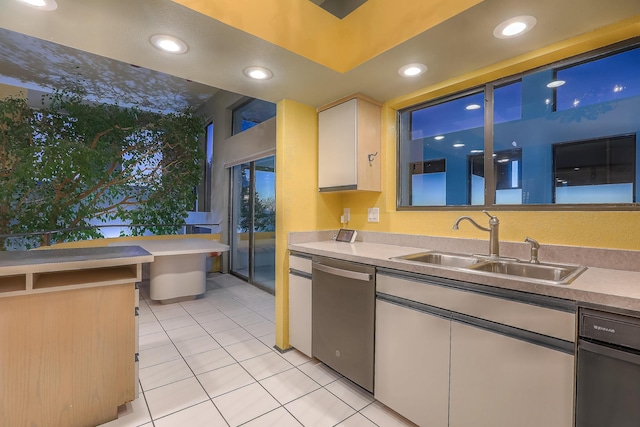 kitchen featuring light tile patterned floors, sink, white cabinets, and stainless steel dishwasher