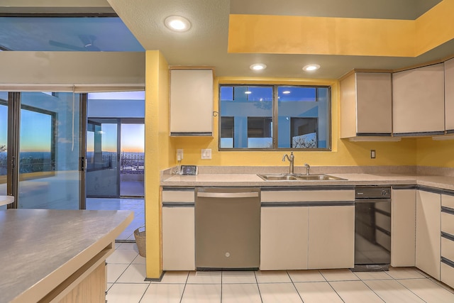 kitchen featuring light tile patterned floors, stainless steel dishwasher, white cabinets, and sink