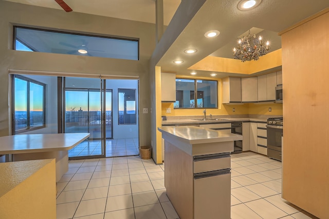 kitchen featuring appliances with stainless steel finishes, stainless steel counters, sink, a notable chandelier, and light tile patterned floors