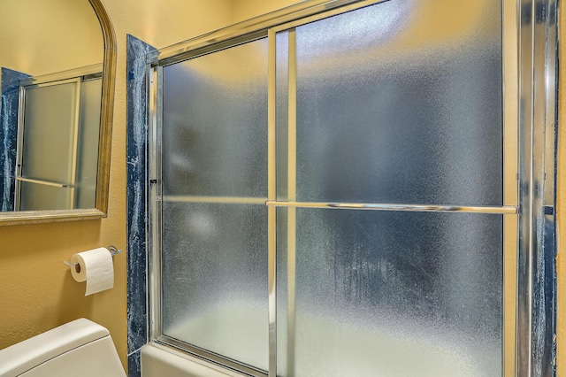 bathroom with enclosed tub / shower combo and toilet