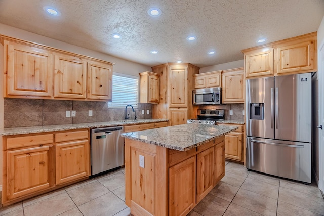 kitchen with light tile patterned flooring, stainless steel appliances, a kitchen island, and light stone counters