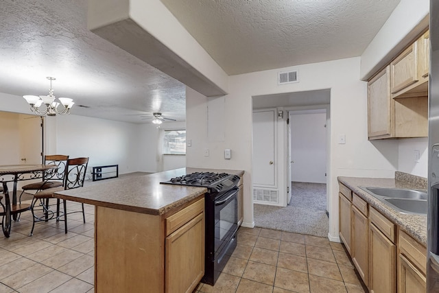 kitchen featuring light tile patterned floors, black gas range, hanging light fixtures, a textured ceiling, and light brown cabinets