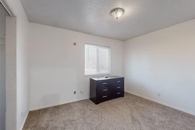 spare room featuring light carpet and a textured ceiling