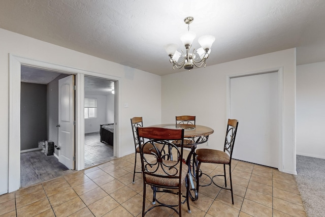 tiled dining area with a notable chandelier and a textured ceiling