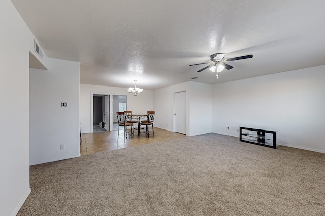 unfurnished living room featuring light colored carpet, ceiling fan with notable chandelier, and a textured ceiling