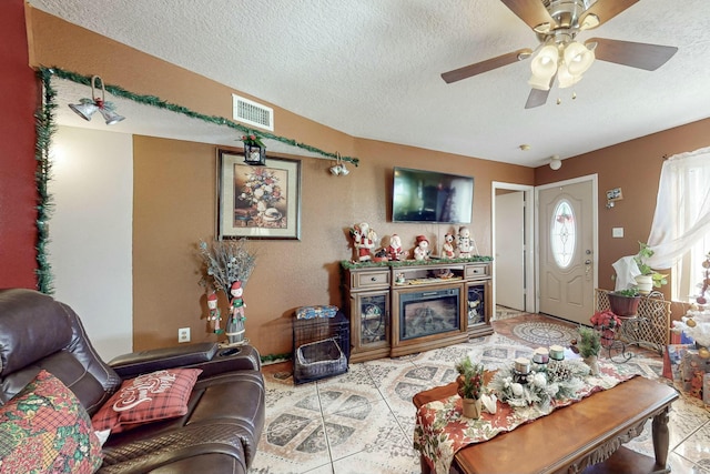 tiled living room with ceiling fan and a textured ceiling