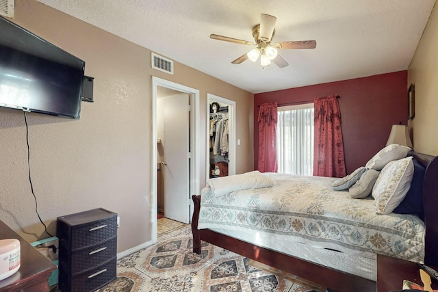 bedroom with a textured ceiling, a closet, a spacious closet, and ceiling fan