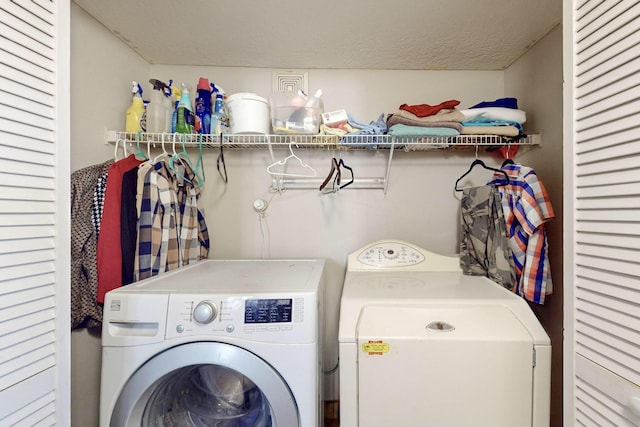 clothes washing area featuring a textured ceiling and washing machine and dryer