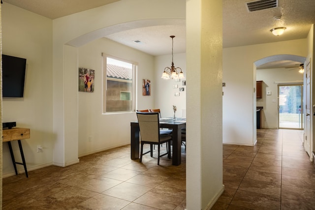 dining area with ceiling fan with notable chandelier, a textured ceiling, and a wealth of natural light