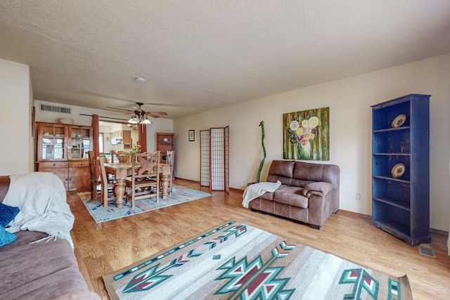 living room with ceiling fan, a textured ceiling, and hardwood / wood-style floors