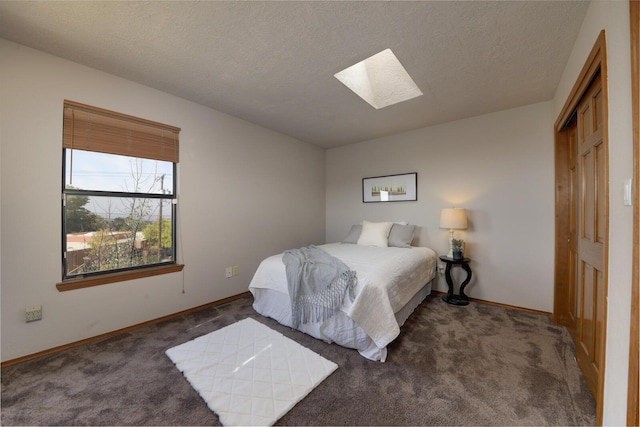 carpeted bedroom featuring a textured ceiling and a skylight