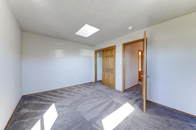 unfurnished bedroom featuring a skylight, a closet, carpet, and a textured ceiling