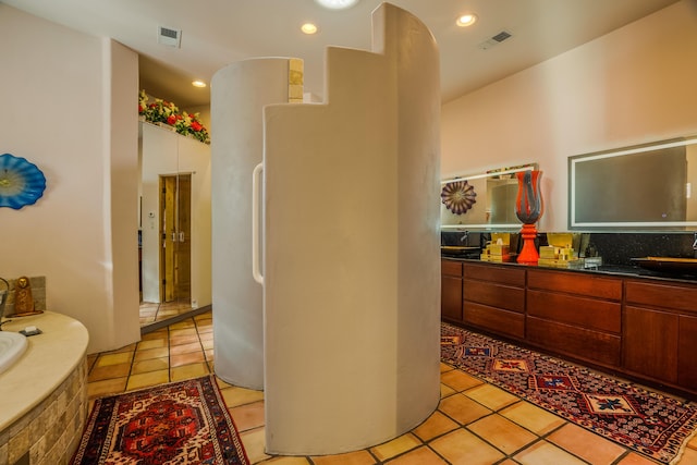 bathroom with tile patterned floors, vanity, and tiled bath