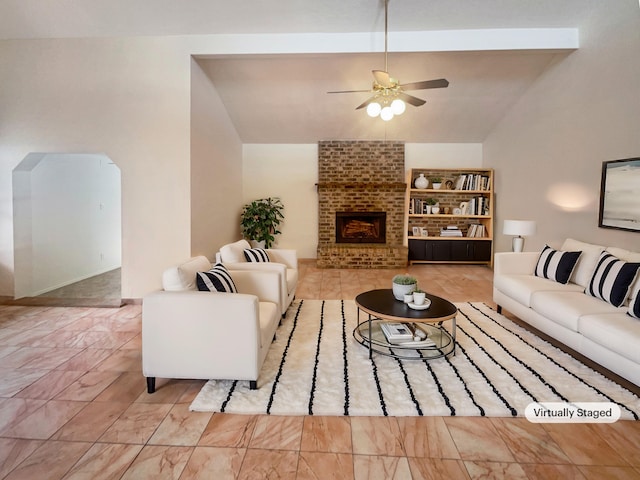 living room featuring a fireplace, lofted ceiling with beams, and ceiling fan