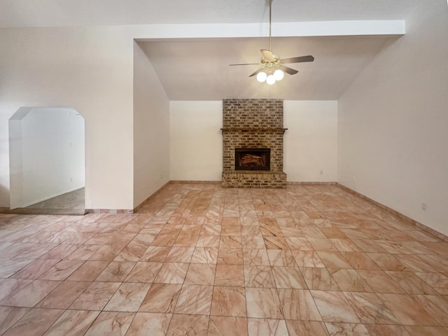 unfurnished living room featuring lofted ceiling with beams, a brick fireplace, and ceiling fan