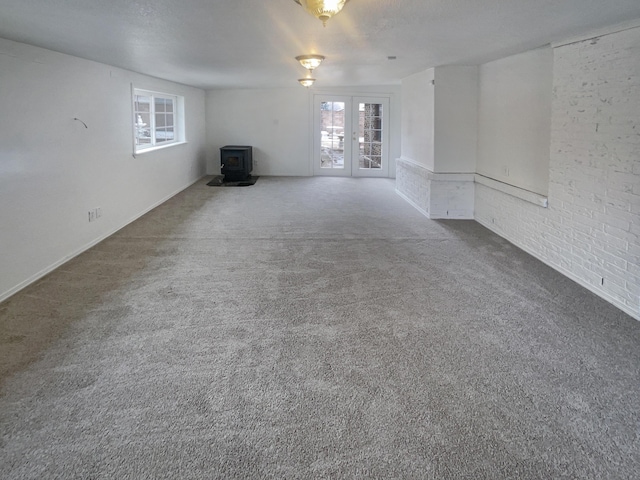 unfurnished living room featuring french doors, carpet, and a wood stove