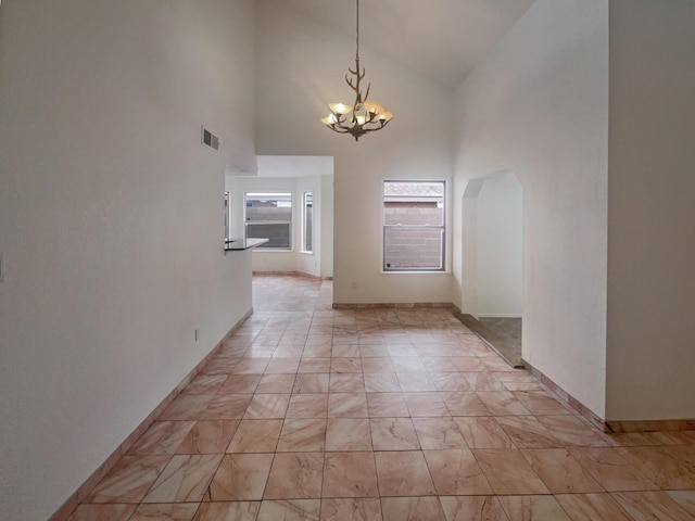 hallway with a high ceiling and an inviting chandelier