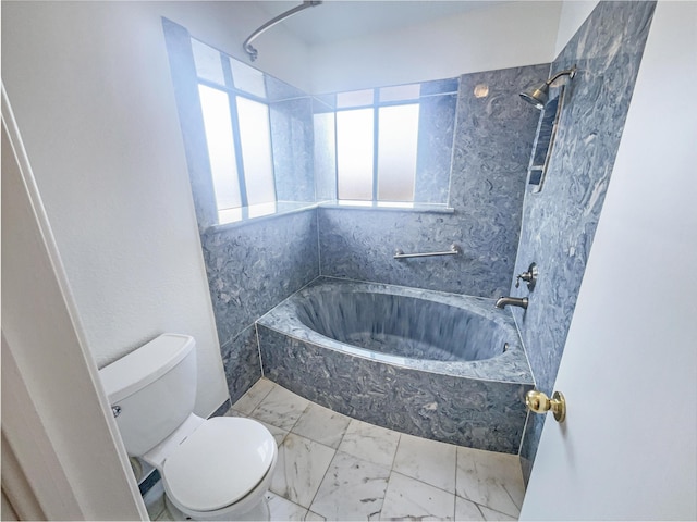 bathroom with tiled shower / bath combo and toilet