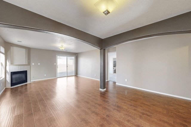 unfurnished living room with hardwood / wood-style flooring, a textured ceiling, and a tile fireplace