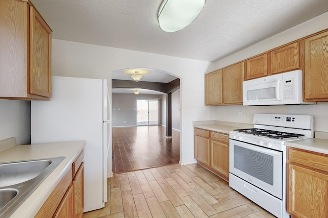 kitchen with sink, white appliances, and light brown cabinets