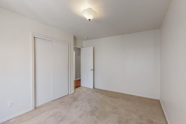 unfurnished bedroom with light carpet and a closet