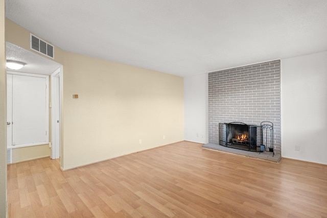 unfurnished living room featuring light wood-type flooring and a brick fireplace