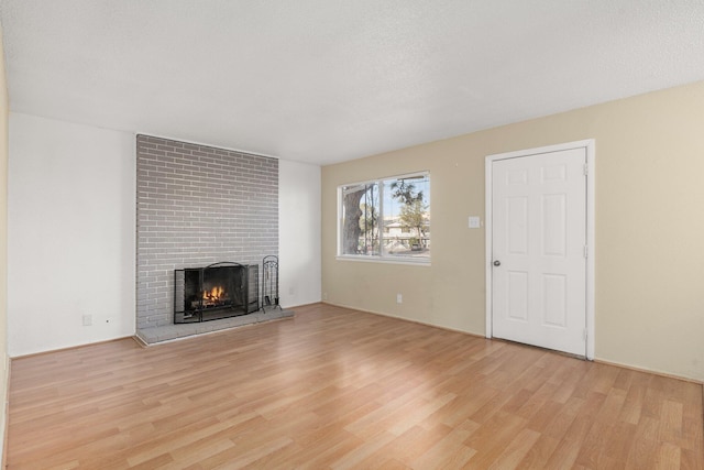 unfurnished living room with a brick fireplace and light hardwood / wood-style floors