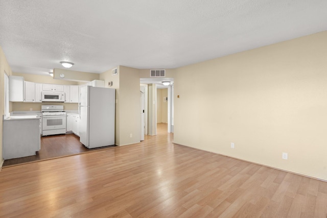 unfurnished living room with a textured ceiling and light hardwood / wood-style flooring