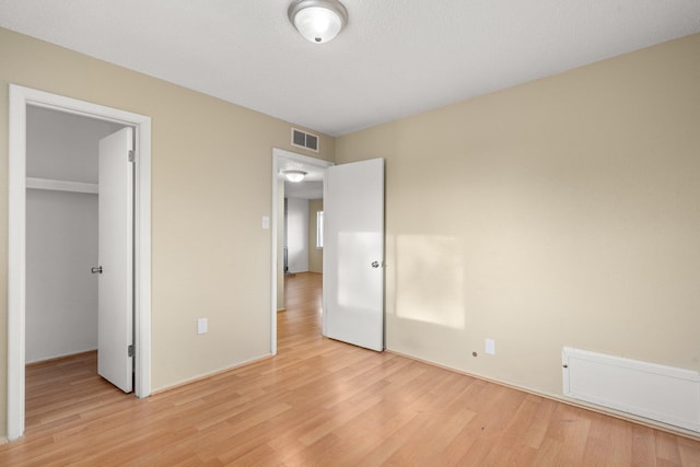 unfurnished bedroom featuring light hardwood / wood-style floors, a spacious closet, and a closet