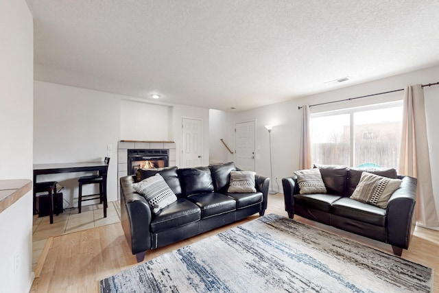 living room with a fireplace, light hardwood / wood-style floors, and a textured ceiling