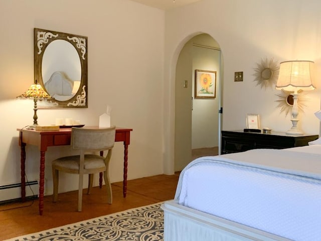 bedroom featuring a baseboard radiator, arched walkways, and wood finished floors