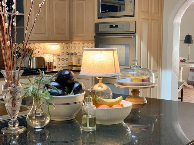 interior space with dark countertops, built in microwave, oven, arched walkways, and backsplash
