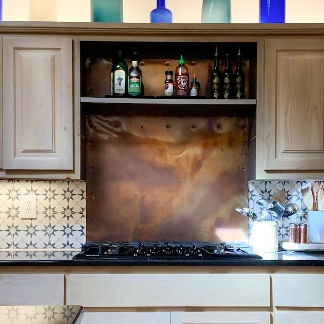 interior details with black gas stovetop, dark countertops, and backsplash