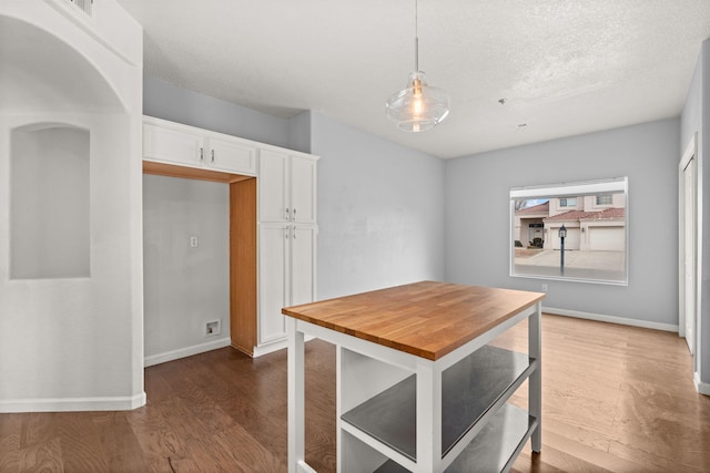 dining room with dark wood-style floors, a textured ceiling, and baseboards