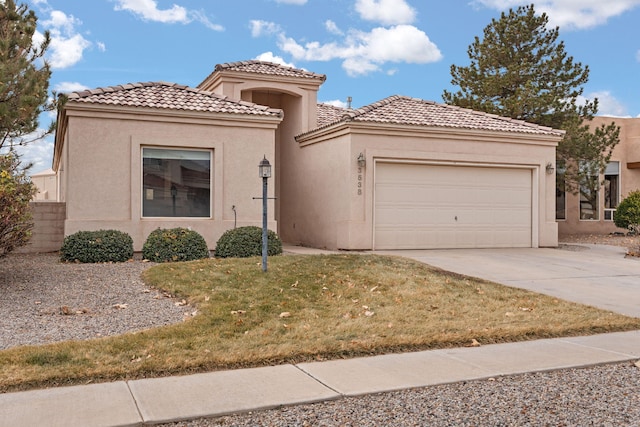 mediterranean / spanish home with concrete driveway, stucco siding, a tile roof, an attached garage, and a front yard