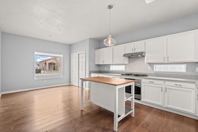 kitchen with under cabinet range hood, butcher block countertops, white cabinetry, and stainless steel appliances