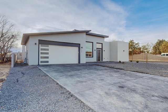 view of front of home with stucco siding, driveway, an attached garage, and fence