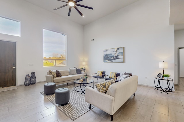 living room with a ceiling fan, baseboards, and a towering ceiling