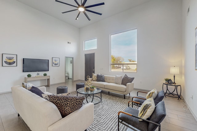 living area featuring visible vents, a high ceiling, light tile patterned floors, baseboards, and ceiling fan