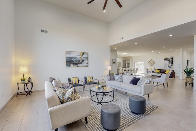 living room featuring visible vents, light wood-style flooring, a towering ceiling, recessed lighting, and ceiling fan