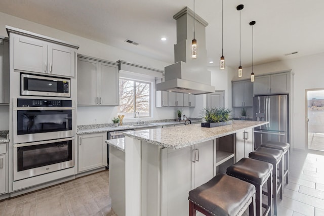 kitchen featuring visible vents, gray cabinets, island exhaust hood, and stainless steel appliances