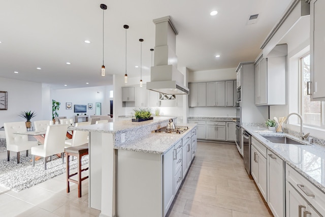 kitchen featuring light stone countertops, recessed lighting, a sink, appliances with stainless steel finishes, and a center island